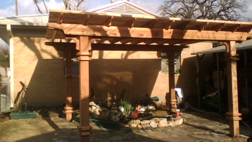 Wooden pergola extending from a house over a small outdoor pond