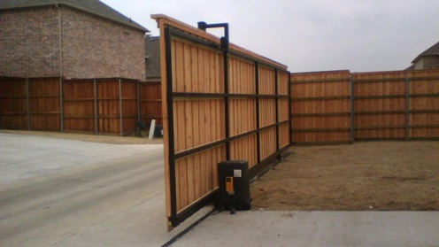 Electronic driveway gate structure attached to wooden fencing allowing access to driveway
