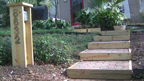 Installed outdoor patio steps featuring paver stones framed in pressure-treated pine lumber and a mailbox